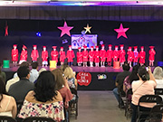 Rows of people watching students on stage in a graduation event